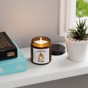 Amber “Radiant & Chic” candle on white shelf beside books and plant, showcasing elegant minimalist home décor by PerfectnElite.